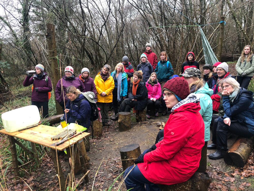 People gathered in the woodland, learning about woodland management