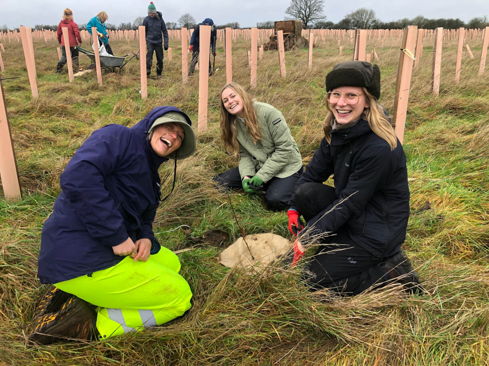 Smiling volunteers planting a tree at Pudding Brook Wood