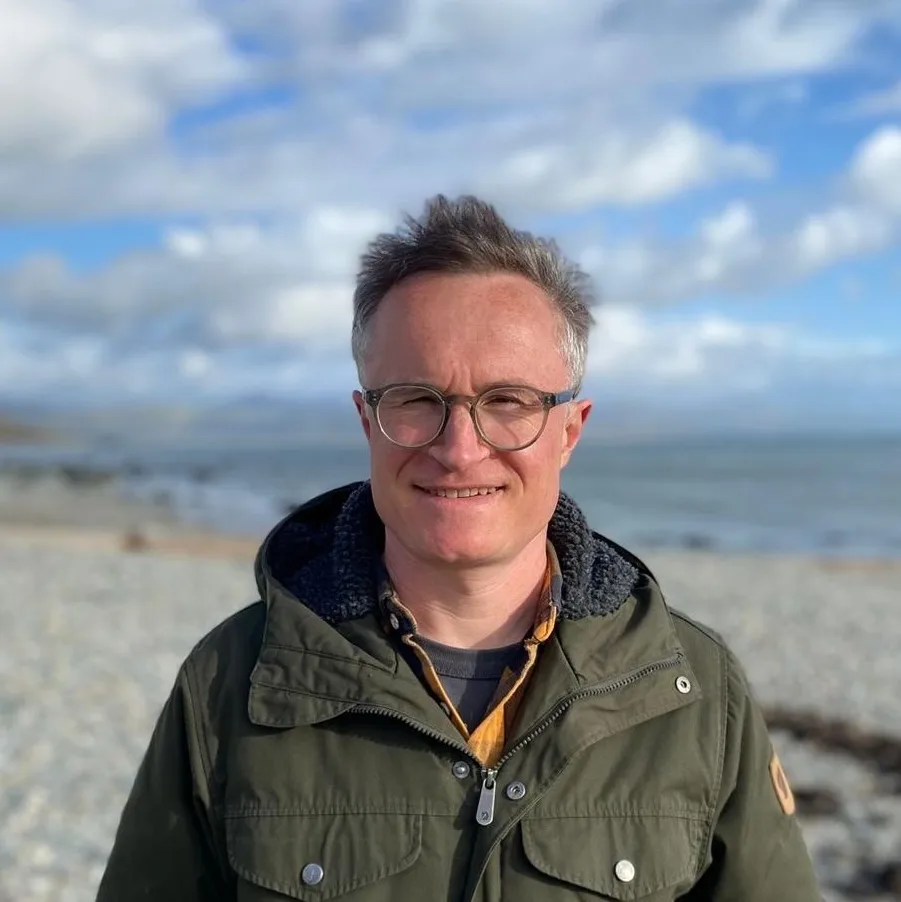 Tom standing on a beach